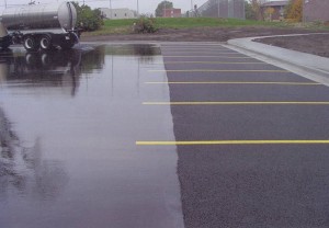 Porous Asphalt, Iowa: A water truck demonstrates how porous pavement at the right drains quickly, while water stands on the conventional pavement at the left. Photo courtesy of NAPA.